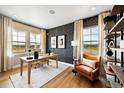 Home office with stylish wallpaper, a modern desk, leather chair, and large windows with views at 8958 Whiteclover St, Littleton, CO 80125