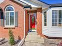 Close-up of the front door showing a red door with glass and the surrounding brick facade at 7809 S Flower St, Littleton, CO 80128