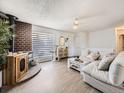 Sun-lit living room with modern floors, white walls, and a wood-burning fireplace at 10895 Fairfax Way, Thornton, CO 80233