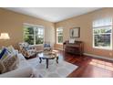 Sun-filled living room boasts hardwood floors, plush seating, a grand piano, and multiple windows for natural light at 744 Kryptonite Dr, Castle Rock, CO 80108