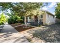 Single-story house featuring a front porch, landscaped yard, and a gravel driveway, offering a welcoming appeal at 4955 Julian St, Denver, CO 80221