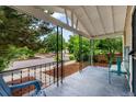 Relaxing covered front porch with seating, wrought iron railing, and views of the lush, tree-lined street at 4955 Julian St, Denver, CO 80221
