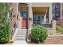 Inviting front entrance with a covered porch, red door with glass, and landscaped bushes at 7814 Inverness Blvd, Englewood, CO 80112