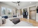 Bright living room with large windows, neutral furnishings, and a ceiling fan at 7814 Inverness Blvd, Englewood, CO 80112