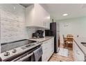 Well-lit kitchen with stainless steel appliances, sleek white cabinets and modern backsplash at 7625 E Quincy Ave # 107, Denver, CO 80237