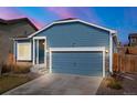 Charming blue home with a two-car garage and stone accents under a clear sky at 8836 Waco Ct, Commerce City, CO 80022