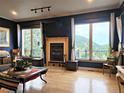 Bright living room with fireplace, mountain views, large windows, and hardwood flooring at 83 Wilderness Cornerstone Rd, Evergreen, CO 80439