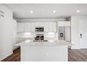 Bright white kitchen featuring an island, modern appliances, and wood-look flooring at 485 Interlocken Blvd # 209, Broomfield, CO 80021