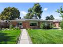 Landscaped front yard featuring a brick home with a walkway leading to a cozy seating area at 2649 N Cook St, Denver, CO 80205