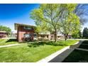 A neat row of townhomes with brick facades and green lawns, sheltered by large, leafy trees at 12632 W Virginia Ave, Lakewood, CO 80228