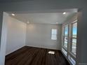 Bright living room with multiple windows, recessed lighting, white walls, and stylish hardwood floors at 7243 Prairie Sage Ln, Littleton, CO 80125