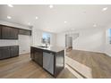 Bright, modern kitchen featuring an island with stainless steel dishwasher and wood flooring at 21134 E 63Rd Dr, Aurora, CO 80019