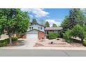 Charming two-story home with lush landscaping, a brick facade, and an attached two-car garage at 1590 S Macon St, Aurora, CO 80012