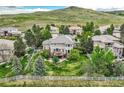 Aerial view of a spacious backyard with a deck, patio, white fence, mature trees, and hillside views at 10529 Dacre Pl, Lone Tree, CO 80124