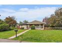 Charming single-story home featuring a covered porch and lush front lawn at 395 Zephyr St, Lakewood, CO 80226
