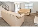 Bright living room featuring neutral carpeting, two comfortable sofas, and modern staircase at 5719 S Lowell Blvd, Littleton, CO 80123