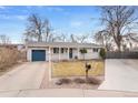 Inviting single-story home featuring a well-manicured lawn, blue garage door and charming front porch at 1359 Chambers Rd, Aurora, CO 80011