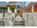 View of the modern home's entrance with concrete stairs, gated walkway, and vibrant yellow door at 2223 W 34Th Ave, Denver, CO 80211