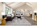 Bright living room featuring vaulted ceilings, a large window, and stylish furniture arrangement on neutral carpet at 7676 S Olive Cir, Centennial, CO 80112