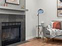 Living room showcasing a fireplace, gray sofa, sleek floor lamp, and hardwood floors for a cozy and modern space at 3001 S Ursula Cir # 101, Aurora, CO 80014