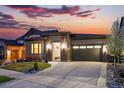 Inviting single-story home with brick accents, garage, and a well-maintained yard at sunset at 6469 Barnstead Dr, Castle Pines, CO 80108