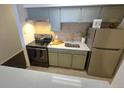 Stylish kitchen includes stainless steel refrigerator, range, and updated countertops and olive green cabinets at 1020 15Th St # 21M, Denver, CO 80202