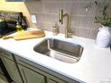 Kitchen sink with gold faucet, white countertops, olive green cabinets, and modern tile backsplash at 1020 15Th St # 21M, Denver, CO 80202