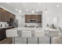 Modern kitchen featuring a large island with seating, stainless steel appliances, and stylish pendant lighting at 6591 N Ceylon St, Denver, CO 80249