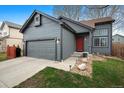Attractive single-Gathering home features a grey exterior with a red door and a two-car garage at 10405 Dresden St, Firestone, CO 80504