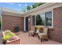 Inviting front porch with wicker chairs, a small table, and colorful potted plants near the front door at 2875 Leyden St, Denver, CO 80207