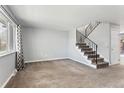 Open living room with a staircase, large window, and neutral carpeting at 6711 S Race St, Centennial, CO 80122