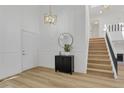 Bright entryway with a modern light fixture, wood-look floors, and staircase to the upper level at 1260 Ascot Ave, Highlands Ranch, CO 80126