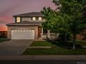Two-story home featuring a brick facade, attached garage, and a well-manicured front yard at twilight at 4816 S Elk Way, Aurora, CO 80016