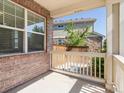 Cozy covered porch area with brick accents and a view of the backyard and a wooden fence at 4816 S Elk Way, Aurora, CO 80016