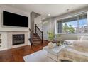 Bright living room with a cozy fireplace, stairs to upper level and a large window at 9071 E Phillips Dr, Centennial, CO 80112