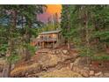Mountain home exterior with deck, surrounded by mature trees and a natural stream at 34788 Forest Estates Rd, Evergreen, CO 80439