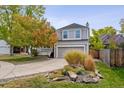 Beautiful landscaping surrounds a two-story house with a gray exterior and a spacious driveway leading to an attached garage at 8510 Union Cir, Arvada, CO 80005