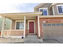 Inviting front porch leads to a classic two-story house with brick accents and a two-car garage at 9703 Ogden Ct, Thornton, CO 80229