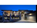 Beautiful home with stone accents, covered decks, and lush landscaping, illuminated by elegant outdoor lighting at 11194 W Yucca, Littleton, CO 80125