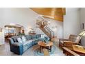 Spacious living room featuring a vaulted ceiling, a wooden staircase, and comfortable seating arrangements at 17420 Caribou Dr, Monument, CO 80132