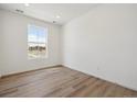Bright, minimalist bedroom with light wood floors, a large window, and white walls at 6646 N Nepal St, Aurora, CO 80019