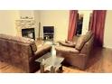 Cozy living room with hardwood floors, a stone fireplace, and comfortable leather seating at 785 Century Ln, Monument, CO 80132