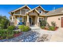 Inviting front entrance featuring stone accents, a blue bench, and lush landscaping at 960 Promontory Cir, Elizabeth, CO 80107
