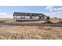 Exterior showcasing black-trim windows, dormers, stone detail, and expansive landscape at 61800 E 32Nd Ct, Strasburg, CO 80136