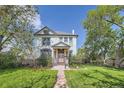 Inviting home with a well-maintained lawn, established trees, and a welcoming front porch at 5127 Lowell Blvd, Denver, CO 80221