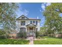Picturesque home with a green lawn, mature trees, and a charming front entry at 5127 Lowell Blvd, Denver, CO 80221