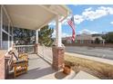 Inviting front porch featuring brick columns, a bench, and an American flag for a warm welcome at 2085 Cactus Bloom Ct, Castle Rock, CO 80109