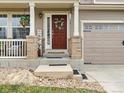 Welcoming front entrance with a red door, decorative wreath, and a charming porch with brick accents at 2468 Candleglow St, Castle Rock, CO 80109