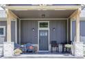 Inviting front porch with stone pillars, outdoor seating, decorative plants, and a stylish front door at 5917 Black Forest Dr, Elizabeth, CO 80107