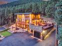 Contemporary home with a private putting green, a fire pit area, a balcony, and an attached garage in a wooded setting at 7793 Elk Path Way, Morrison, CO 80465